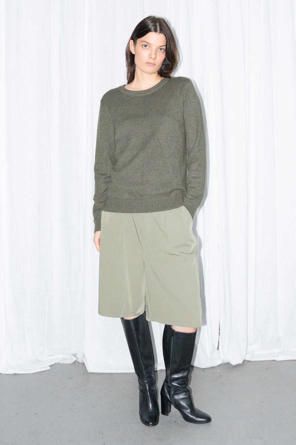 Front view of a dark olive green crew-neck knit sweater with khaki green tailored Bermuda shorts