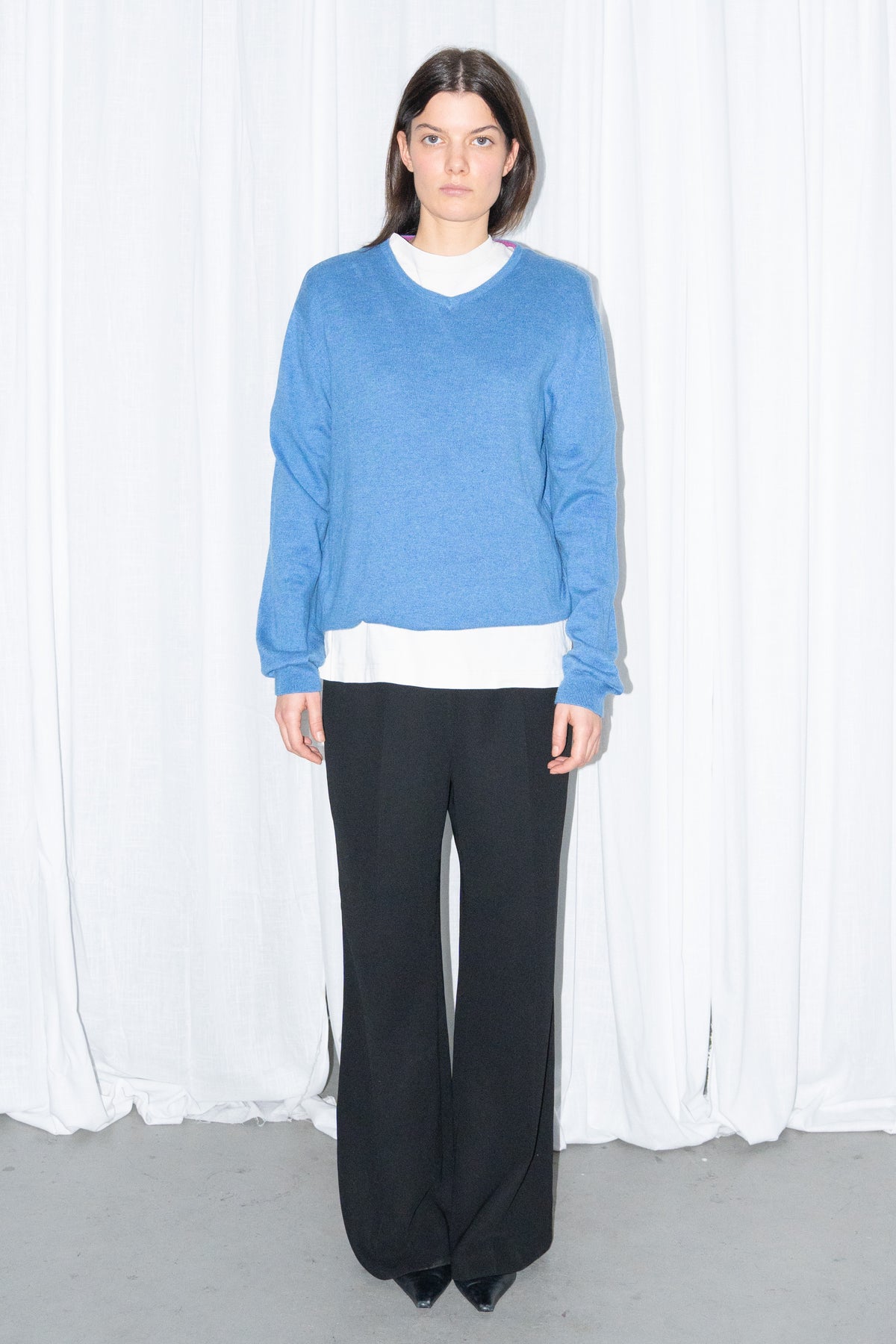 Model wearing blue V-neck knit sweater with black flared trousers – MINIFALDA