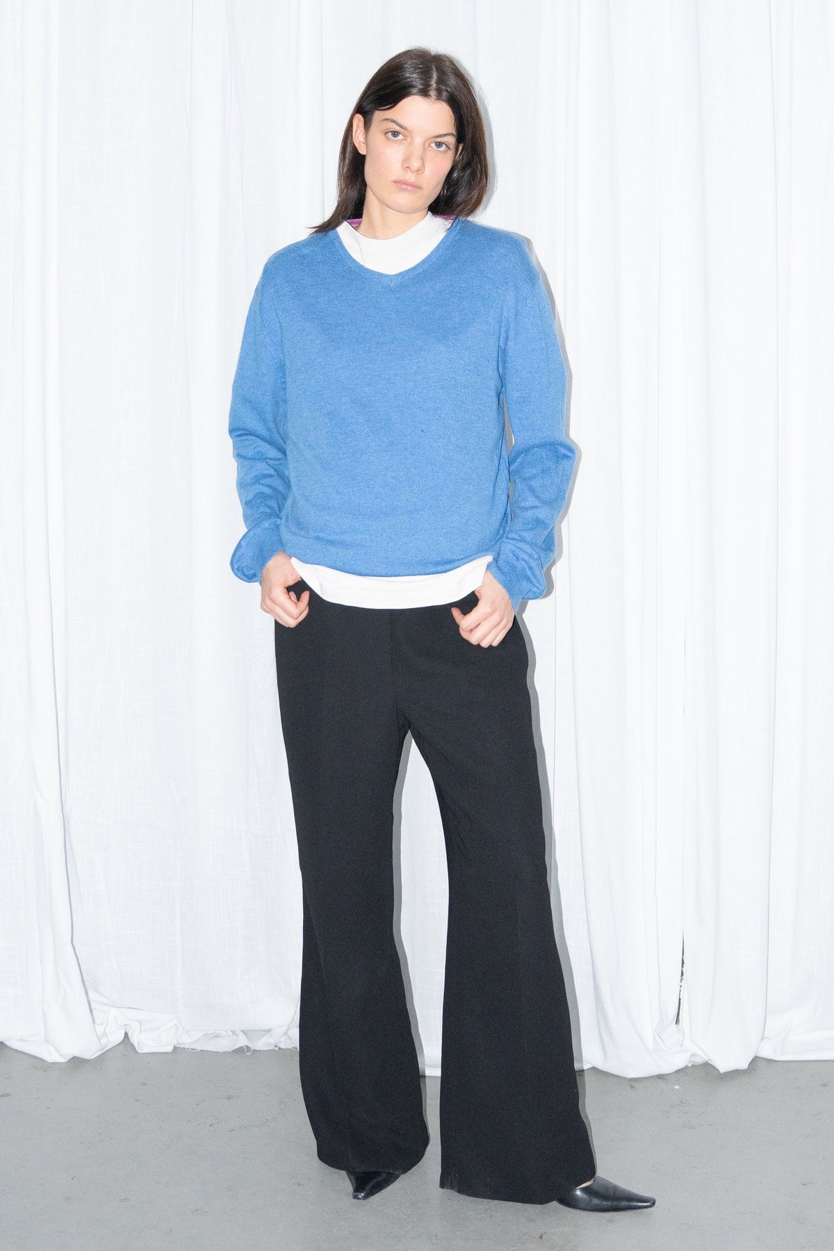 Model wearing blue V-neck knit sweater with black flared trousers – MINIFALDA