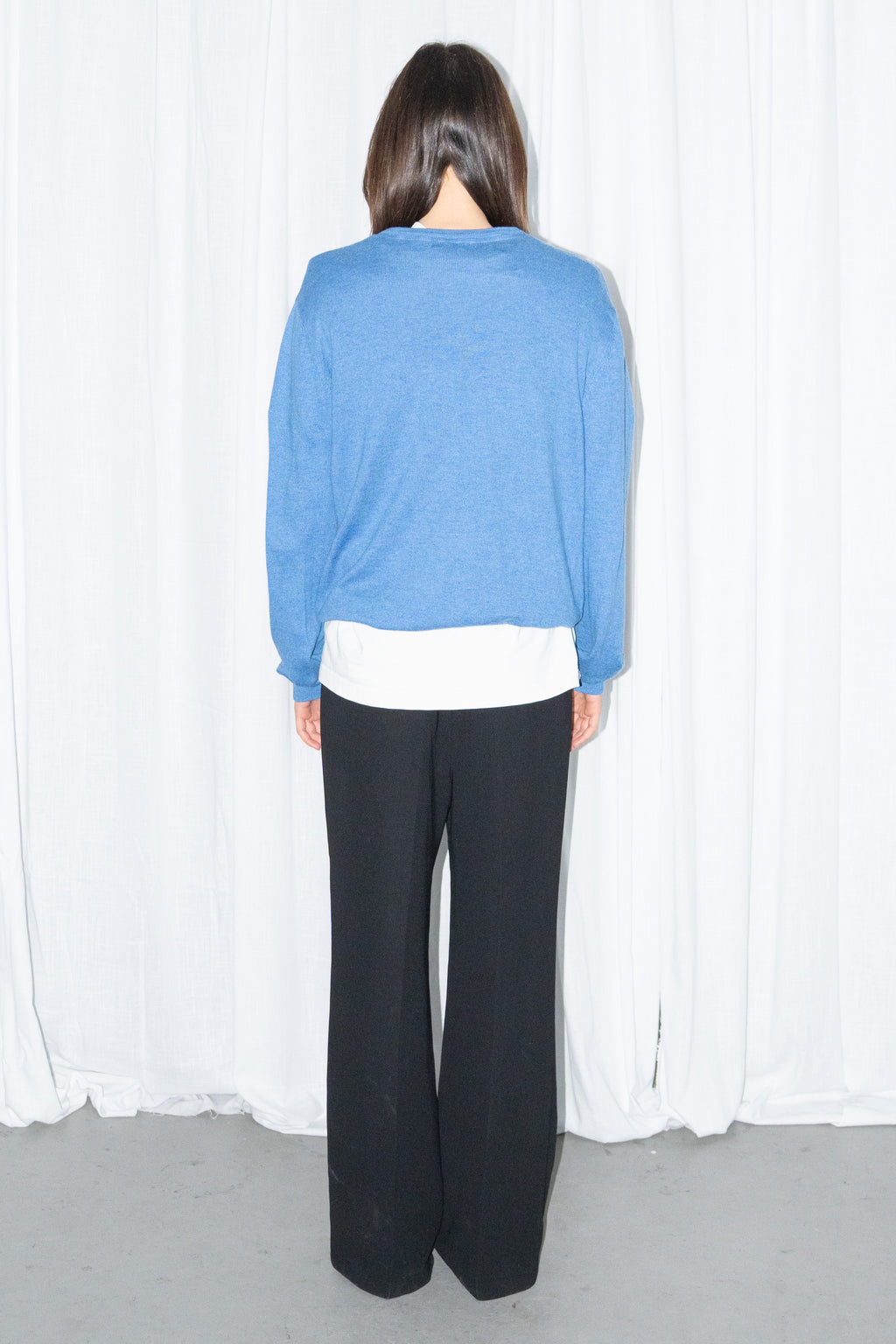 Model wearing blue V-neck knit sweater with black flared trousers – MINIFALDA