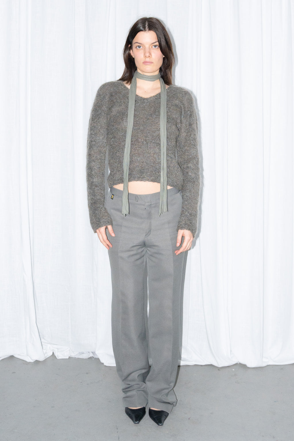 Front view of a grey fluffy cropped mohair knit sweater with grey wide-leg trousers and a grey scarf