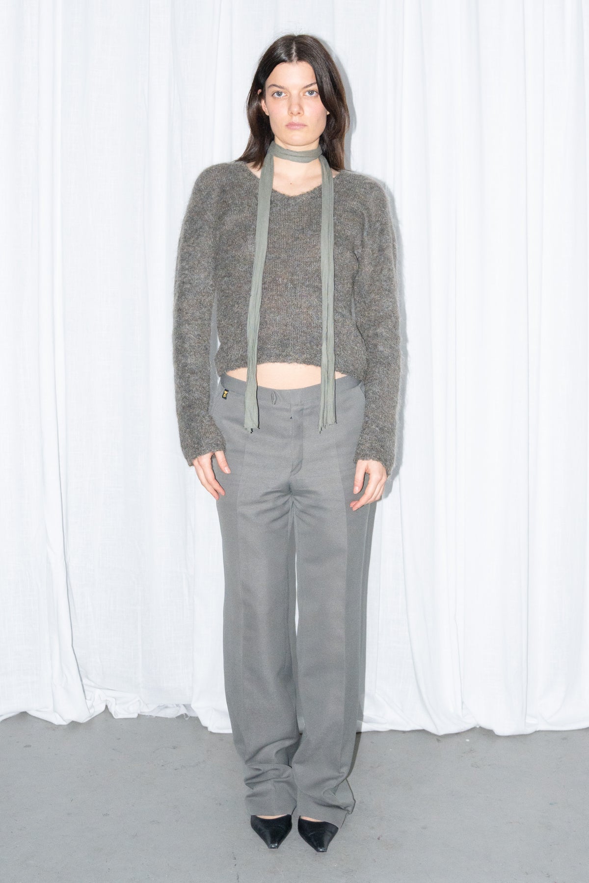 Front view of a grey fluffy cropped mohair knit sweater with grey wide-leg trousers and a grey scarf