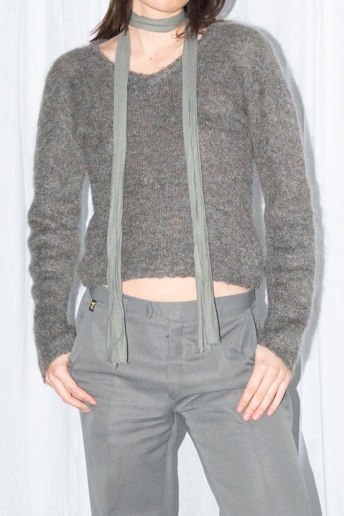 Close-up of a grey fluffy cropped mohair knit sweater with grey wide-leg trousers and a grey scarf