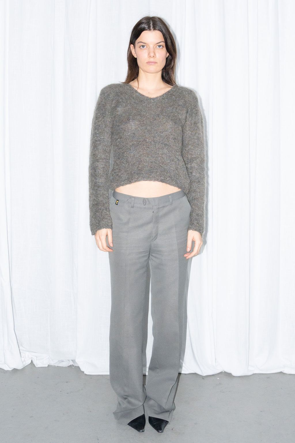Front view of a grey fluffy cropped mohair knit sweater with grey wide-leg trousers and a grey scarf