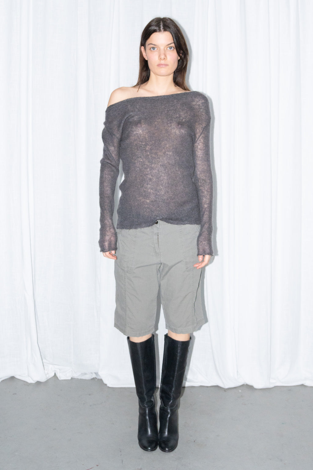 Front view of a charcoal brown off-shoulder fitted top with khaki green cargo Bermuda shorts and black knee boots