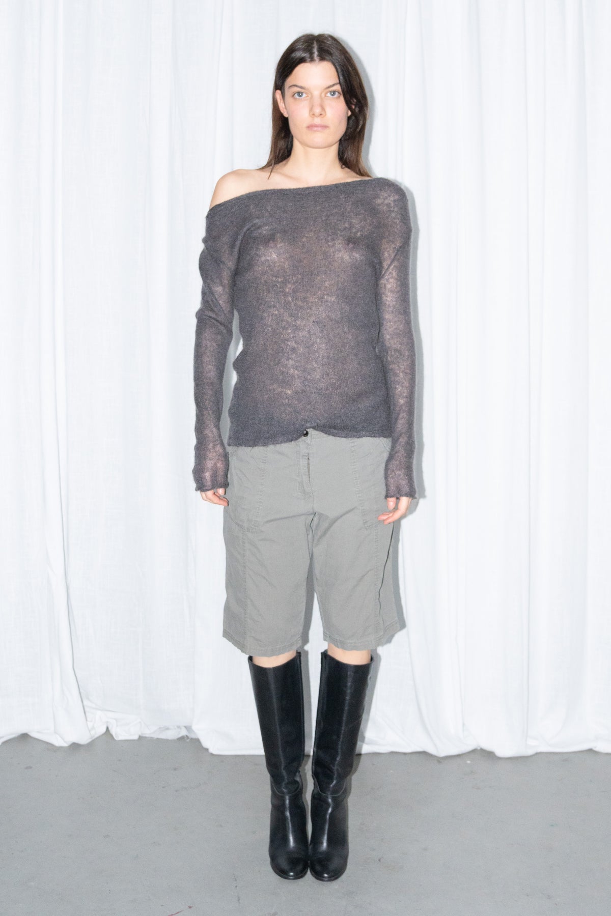 Front view of a charcoal brown off-shoulder fitted top with khaki green cargo Bermuda shorts and black knee boots
