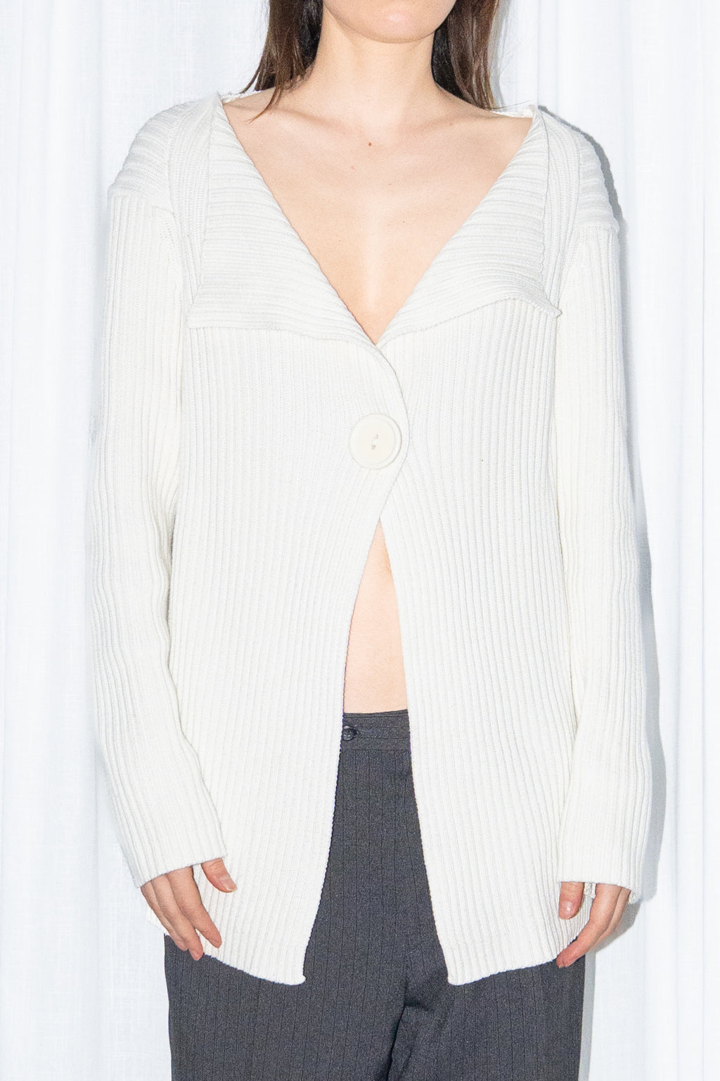 Close-up of a cream ribbed knit long cardigan with black high-waist wide-leg trousers