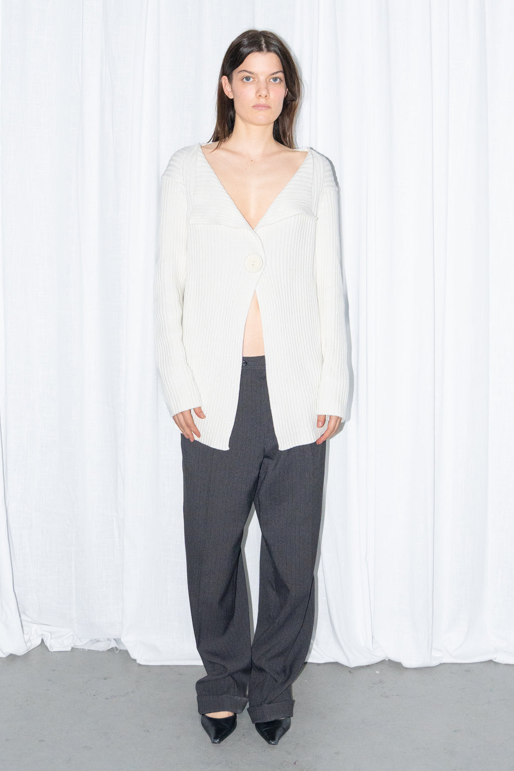 Front view of a cream ribbed knit long cardigan with black high-waist wide-leg trousers