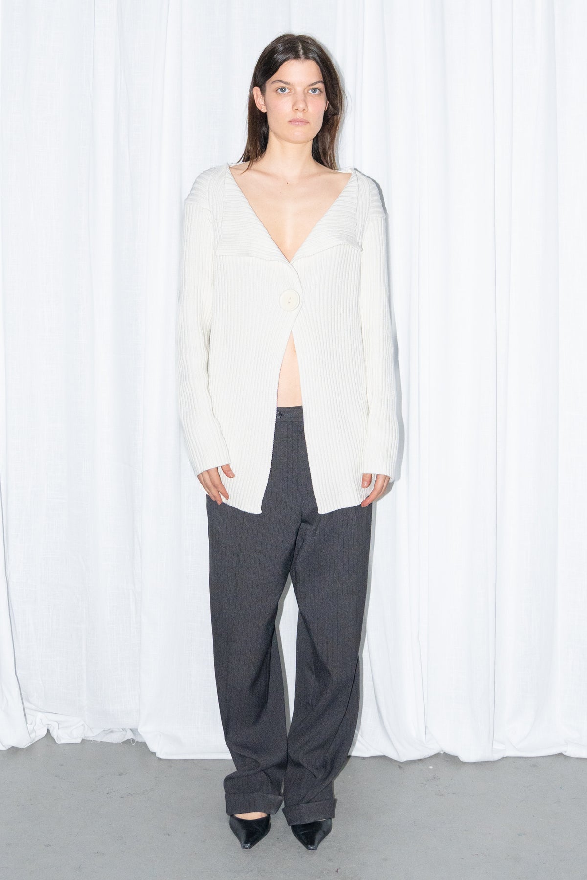 Front view of a cream ribbed knit long cardigan with black high-waist wide-leg trousers