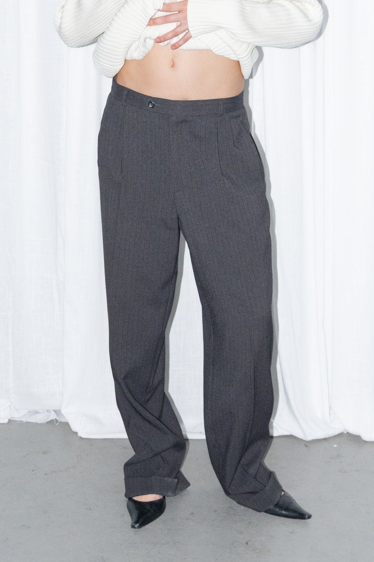 Close-up of black high-waist wide-leg trousers worn with a cream ribbed knit long cardigan