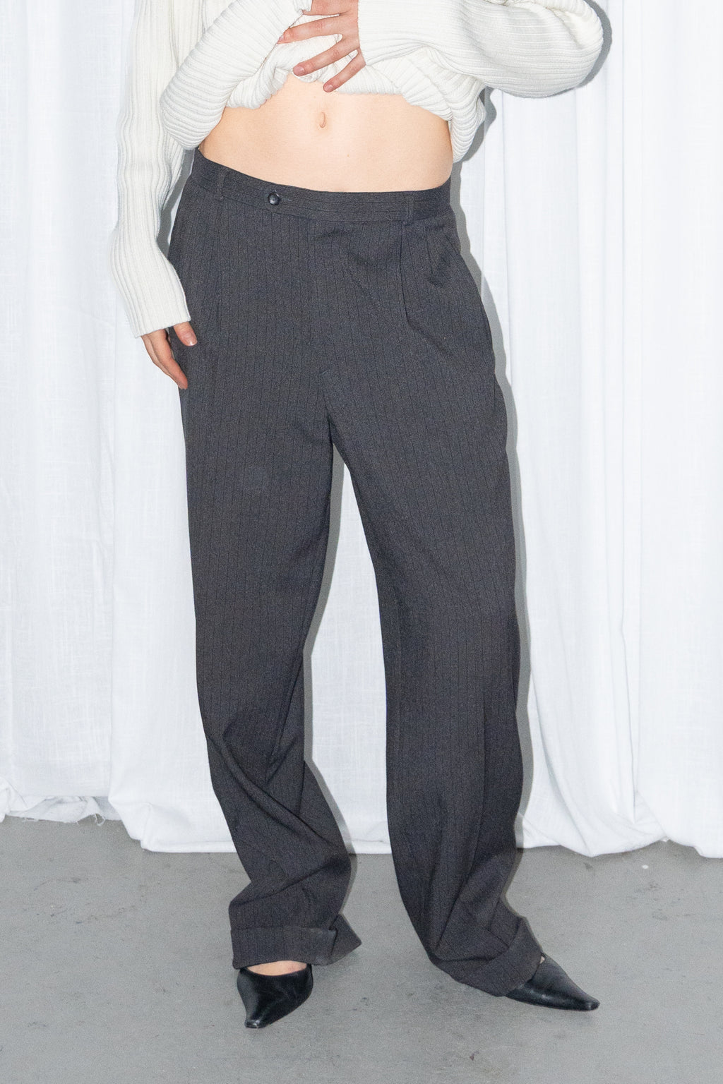 Close-up of black high-waist wide-leg trousers worn with a cream ribbed knit long cardigan