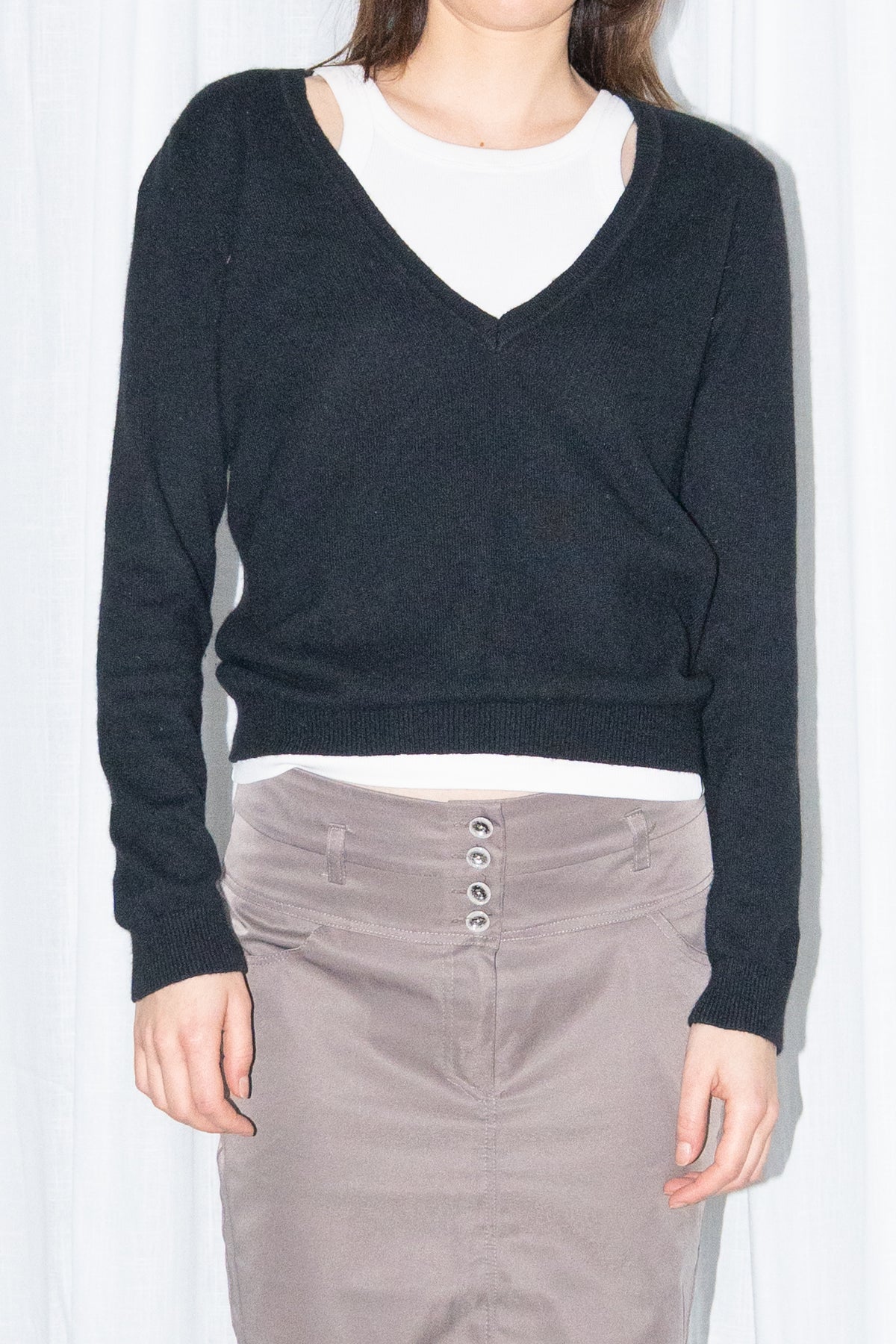 Close-up of a black V-neck knit sweater over a white T-shirt with a brown skirt – MINIFALDA