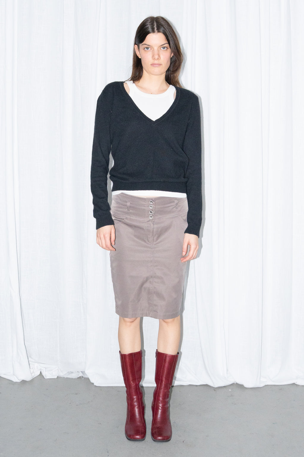 Model wearing a black V-neck knit sweater over a white T-shirt with a brown skirt – MINIFALDA