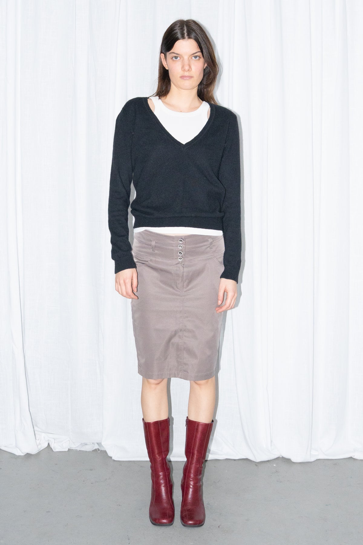 Model wearing a black V-neck knit sweater over a white T-shirt with a brown skirt – MINIFALDA