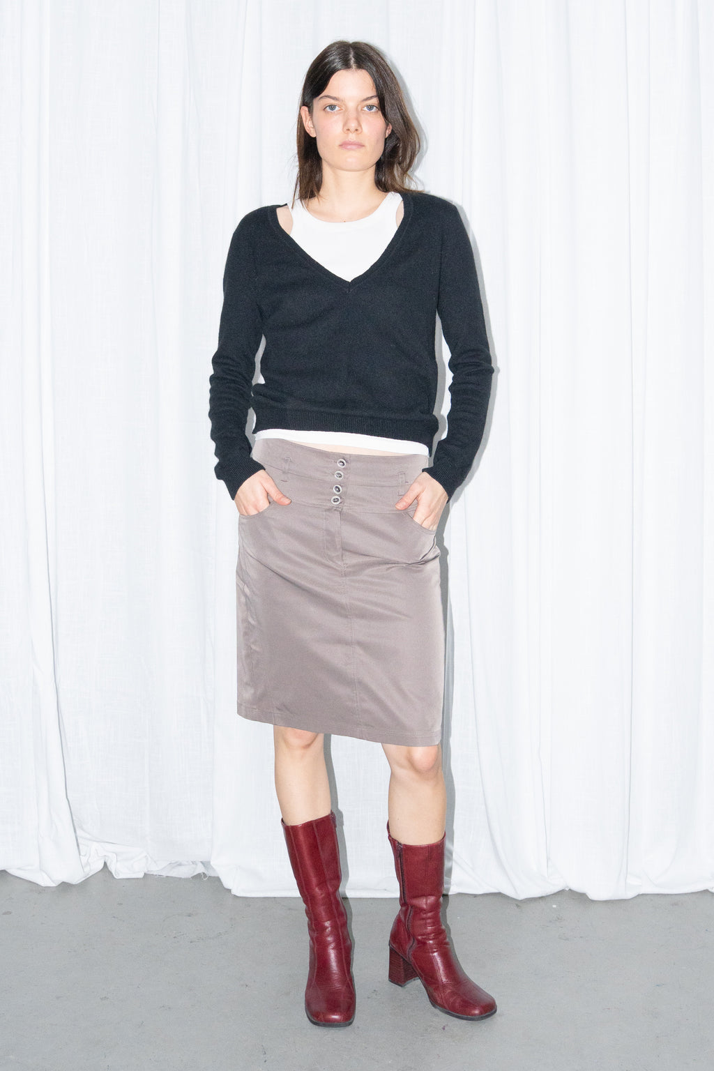 Model wearing a black V-neck knit sweater over a white T-shirt with a brown skirt – MINIFALDA
