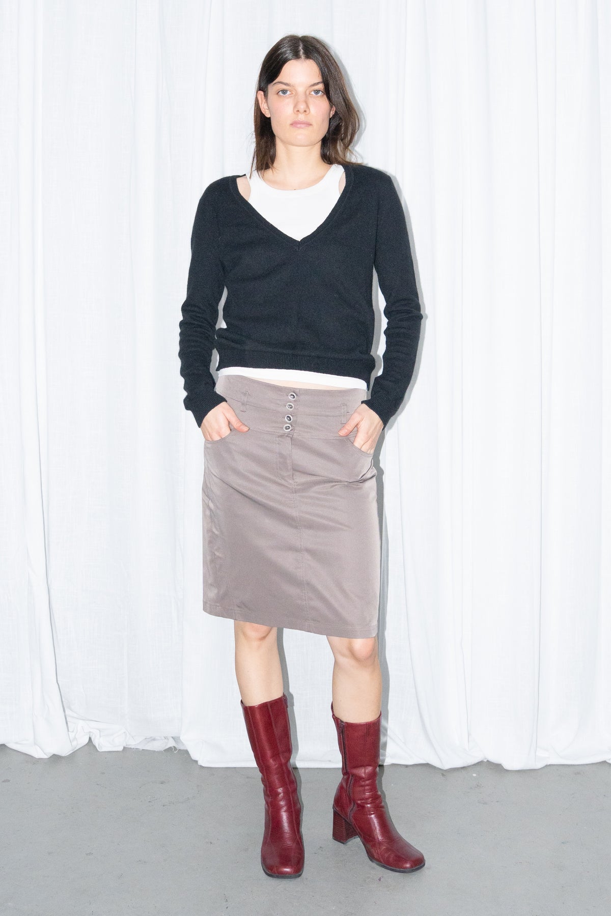 Model wearing a black V-neck knit sweater over a white T-shirt with a brown skirt – MINIFALDA