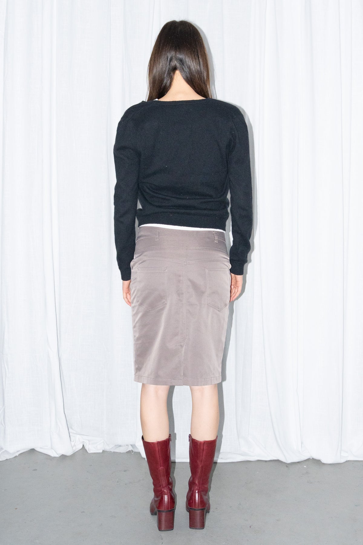 Model wearing a black V-neck knit sweater over a white T-shirt with a brown skirt – MINIFALDA