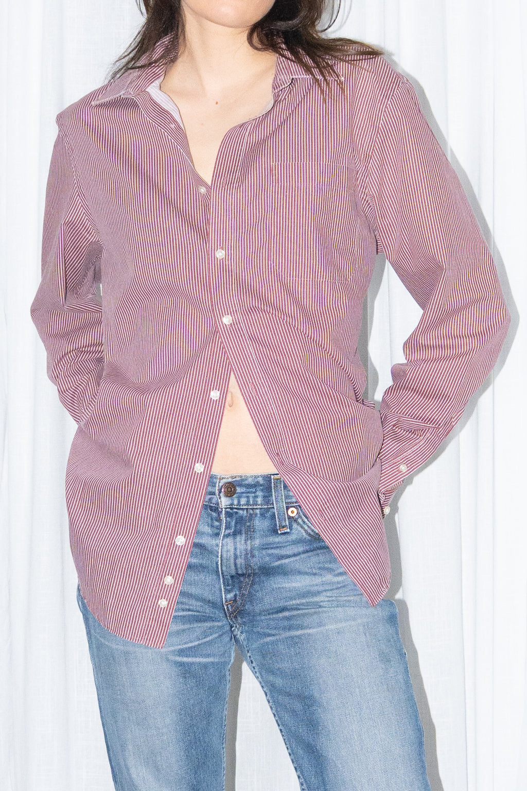 Close-up of a burgundy striped button-up shirt with light blue jeans