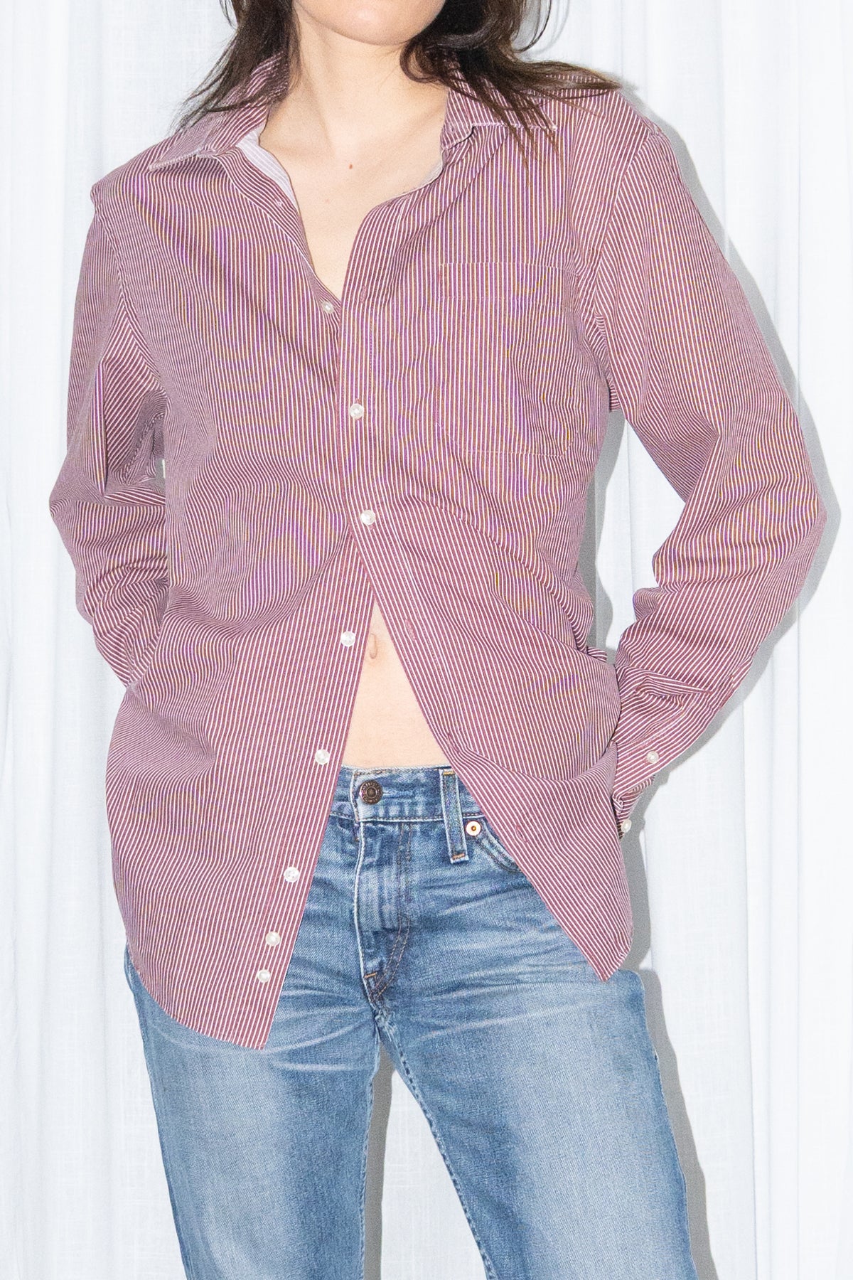 Close-up of a burgundy striped button-up shirt with light blue jeans
