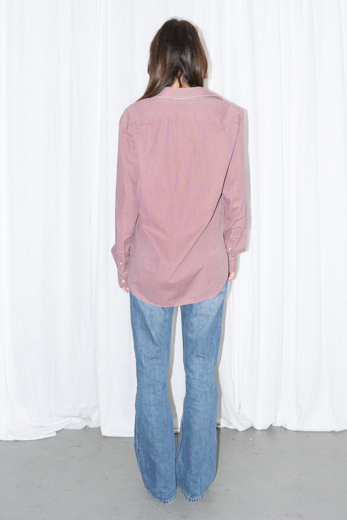 Back view of a burgundy striped button-up shirt with light blue jeans