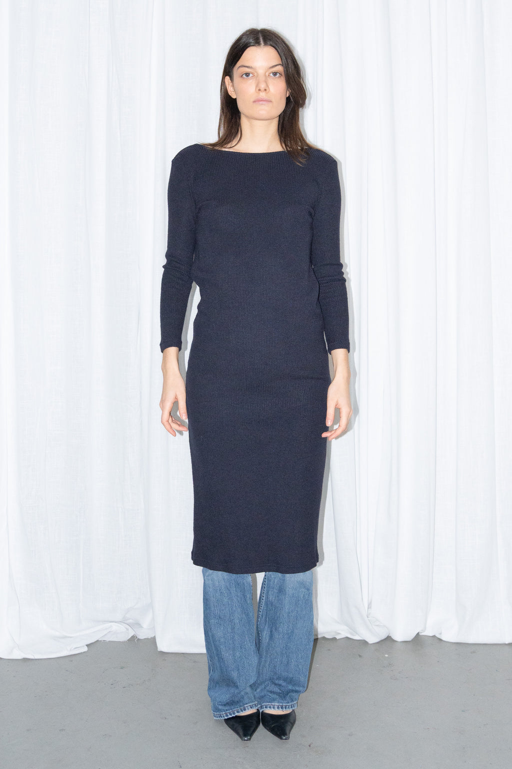 Model wearing a navy asymmetric-neck knit midi dress worn over light blue jeans