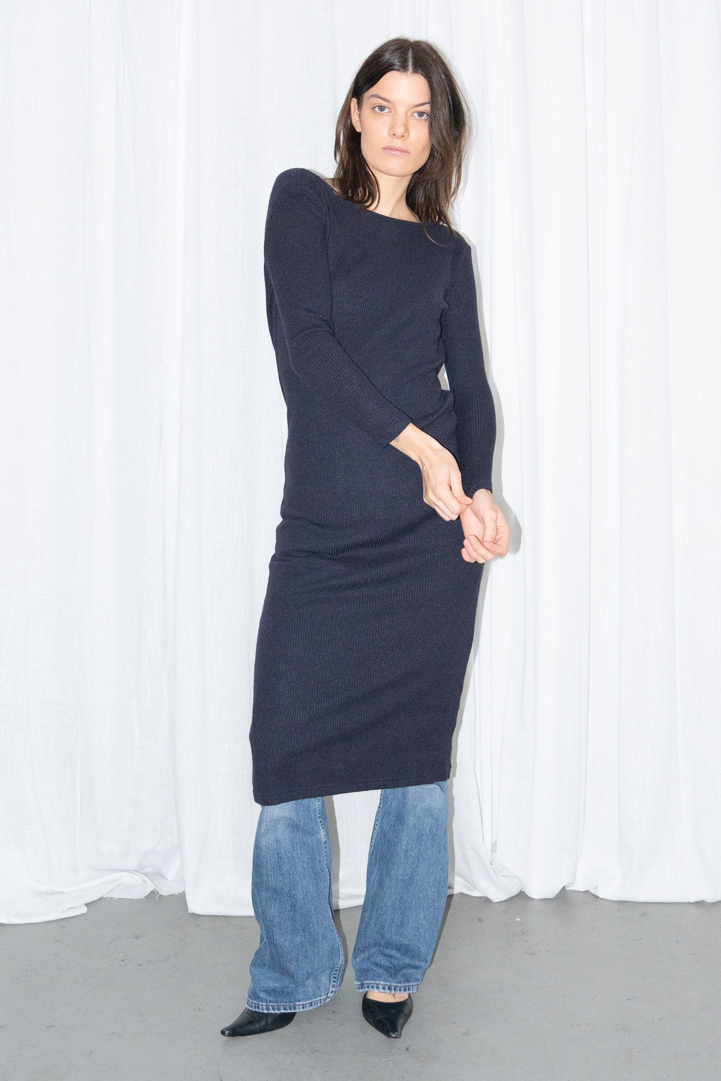 Model wearing a navy asymmetric-neck knit midi dress worn over light blue jeans