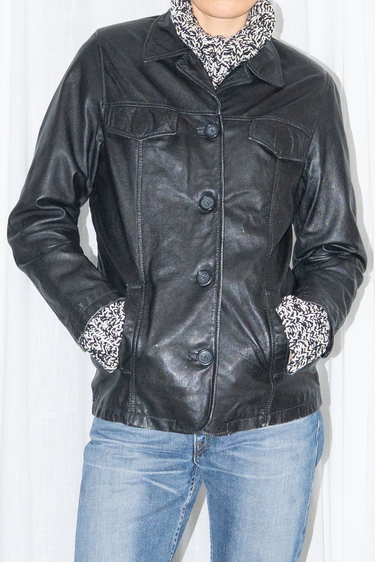 Close-up of black leather shirt jacket over a grey marled knit with light blue jeans – MINIFALDA