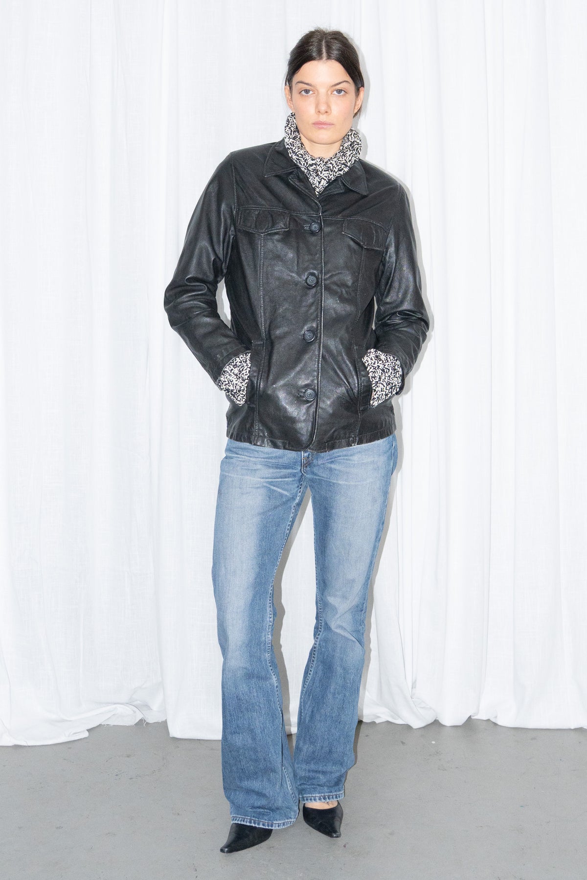 Model wearing black leather shirt jacket over a grey marled knit with light blue jeans – MINIFALDA