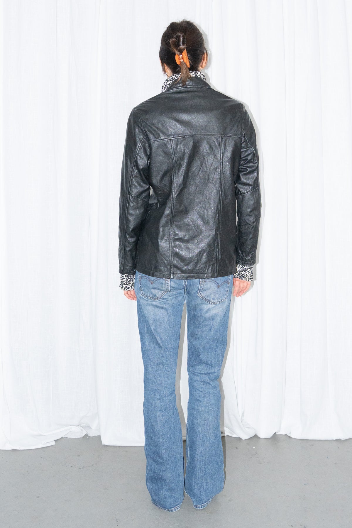 Model wearing black leather shirt jacket over a grey marled knit with light blue jeans – MINIFALDA