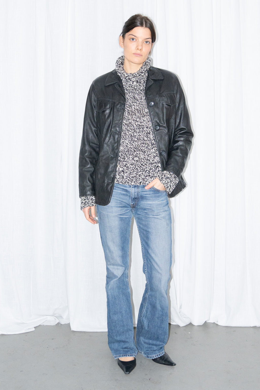 Model wearing black leather shirt jacket over a grey marled knit with light blue jeans – MINIFALDA