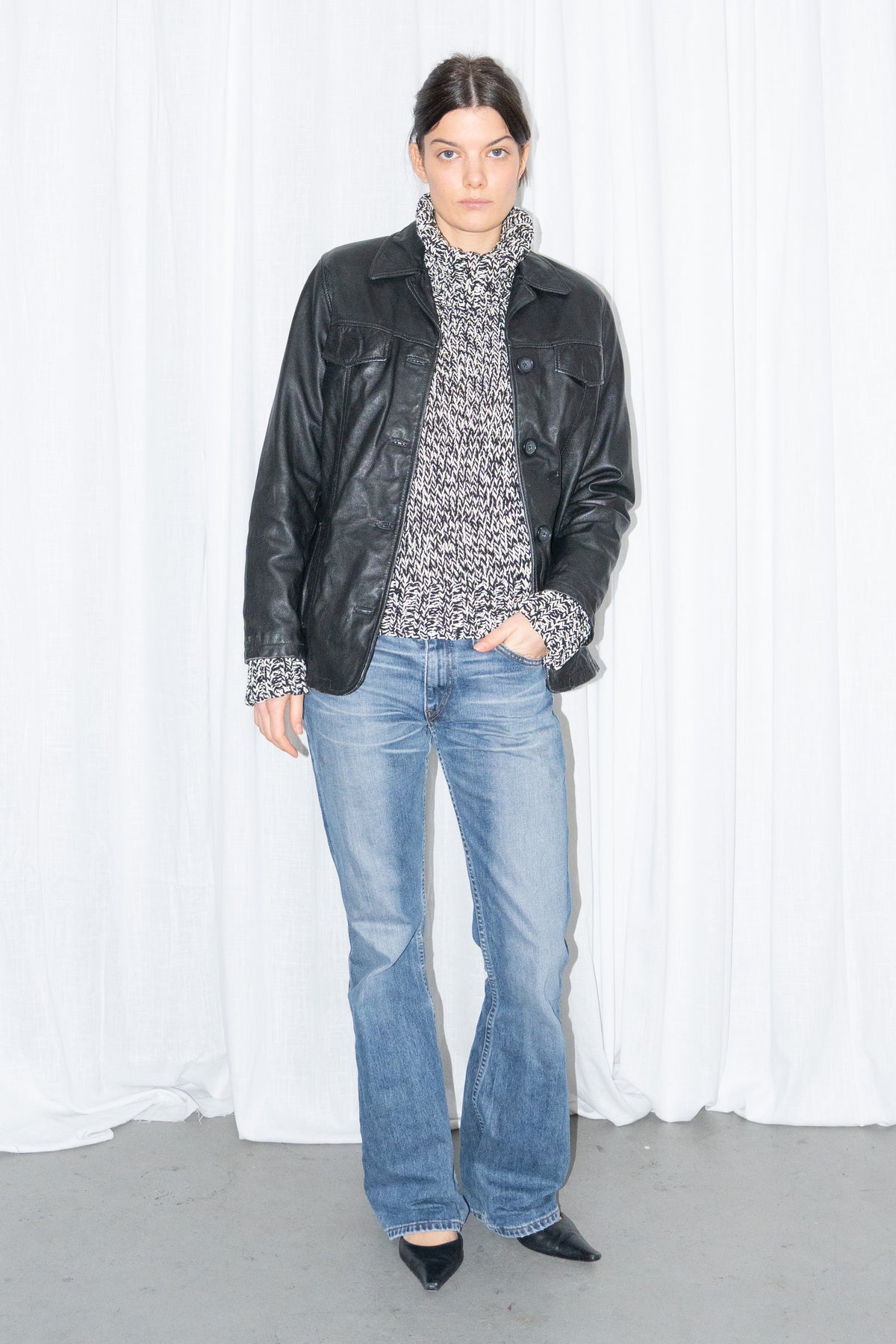 Model wearing black leather shirt jacket over a grey marled knit with light blue jeans – MINIFALDA