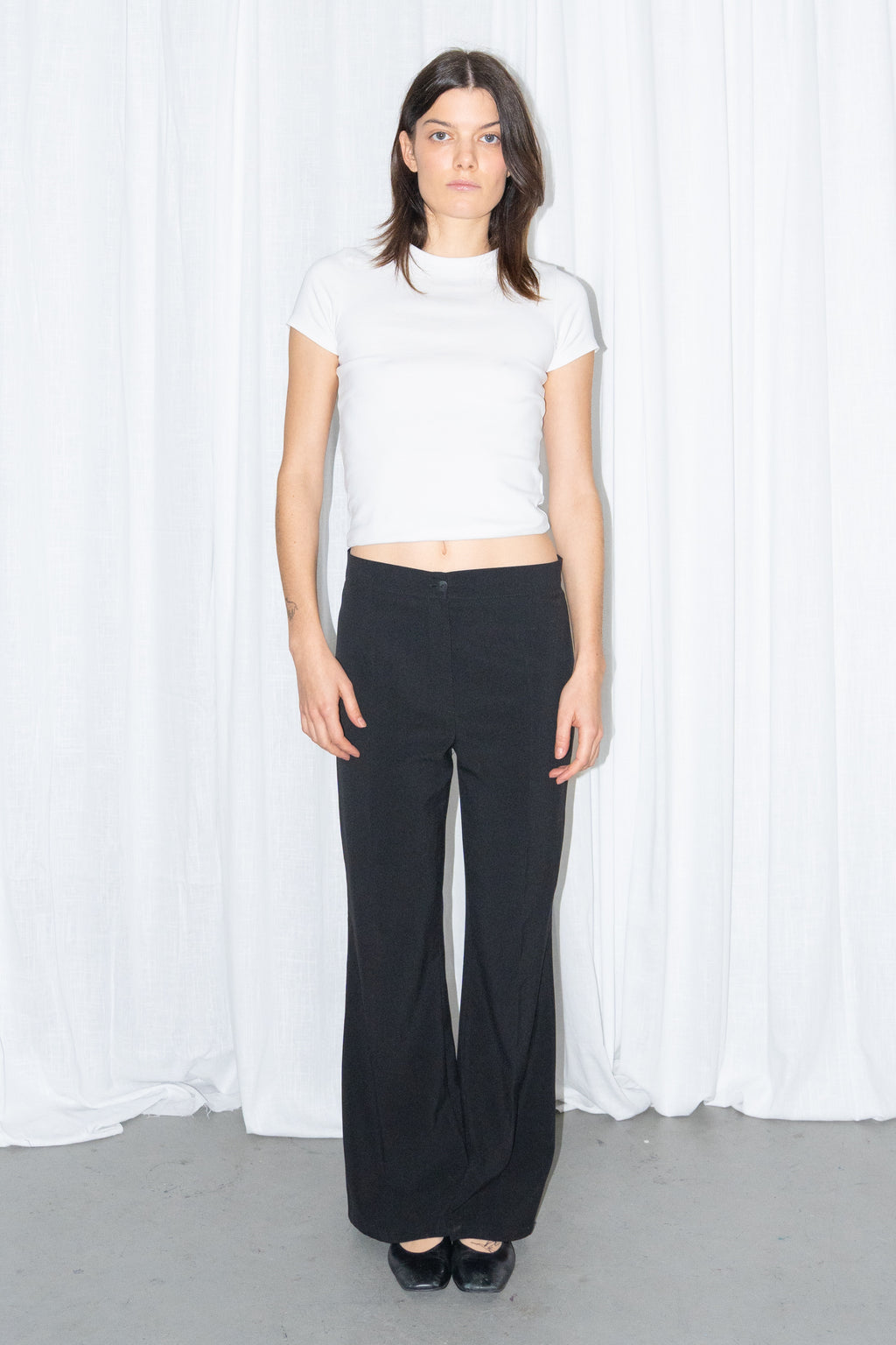 Model wearing a white fitted T-shirt with black low-rise trousers