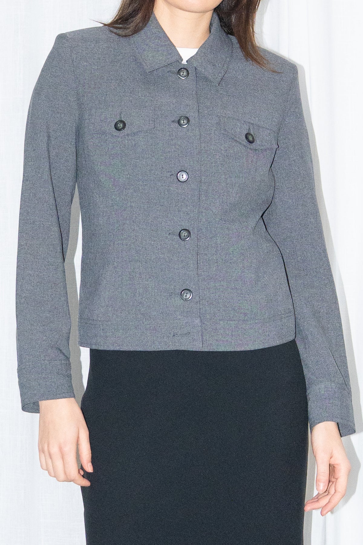Close-up of a grey 5-pocket blazer jacket with a white T-shirt and a black flared midi skirt over black trousers