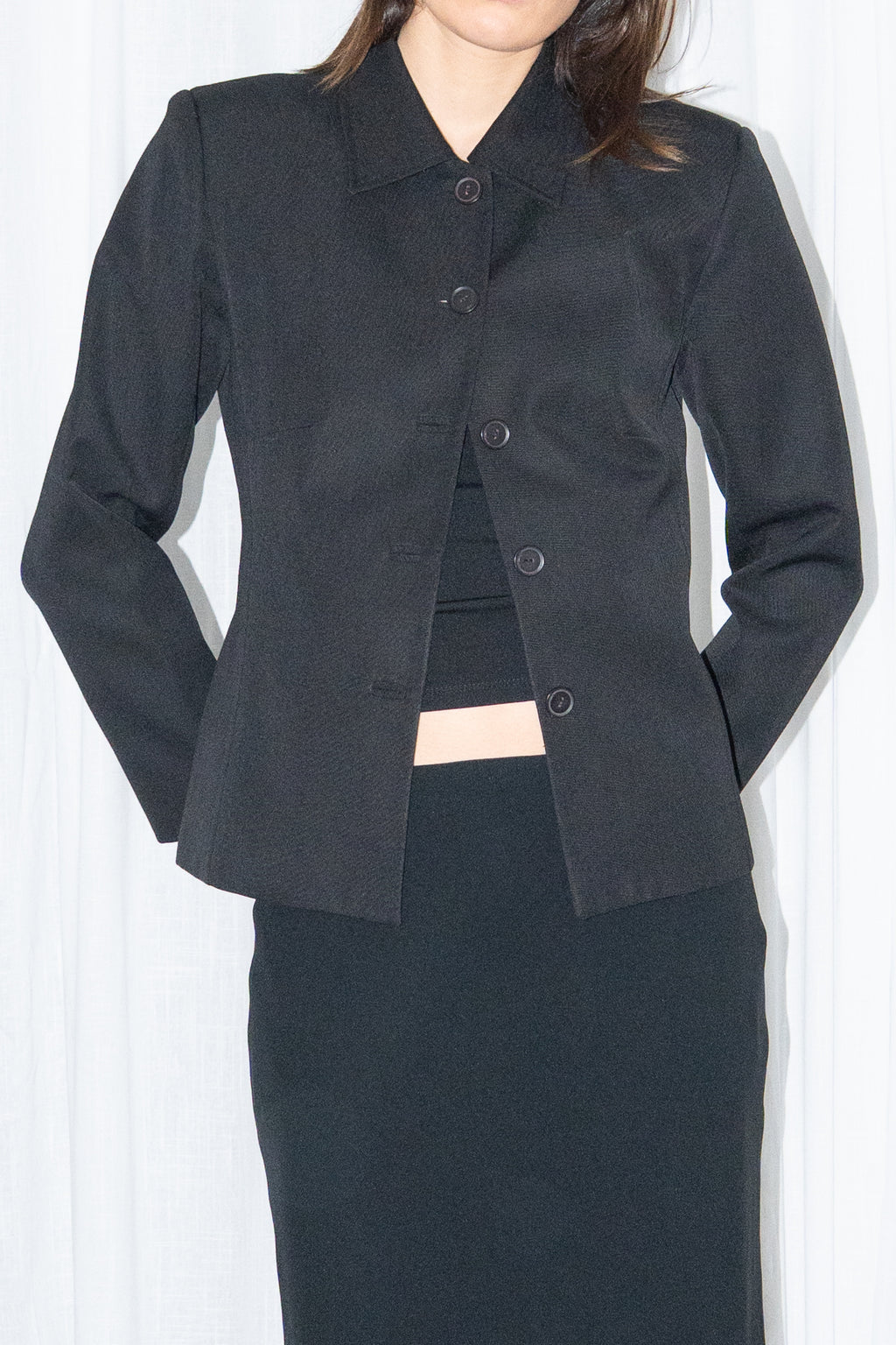 Close-up of black boxy button-up jacket with a black flared midi skirt over black trousers – MINIFALDA