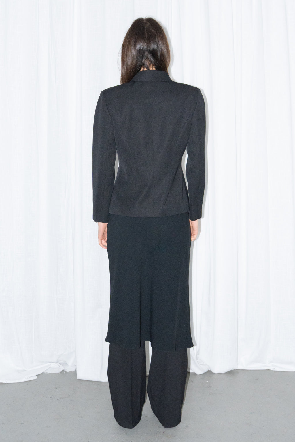 Model wearing black boxy button-up jacket with a black flared midi skirt over black trousers – MINIFALDA