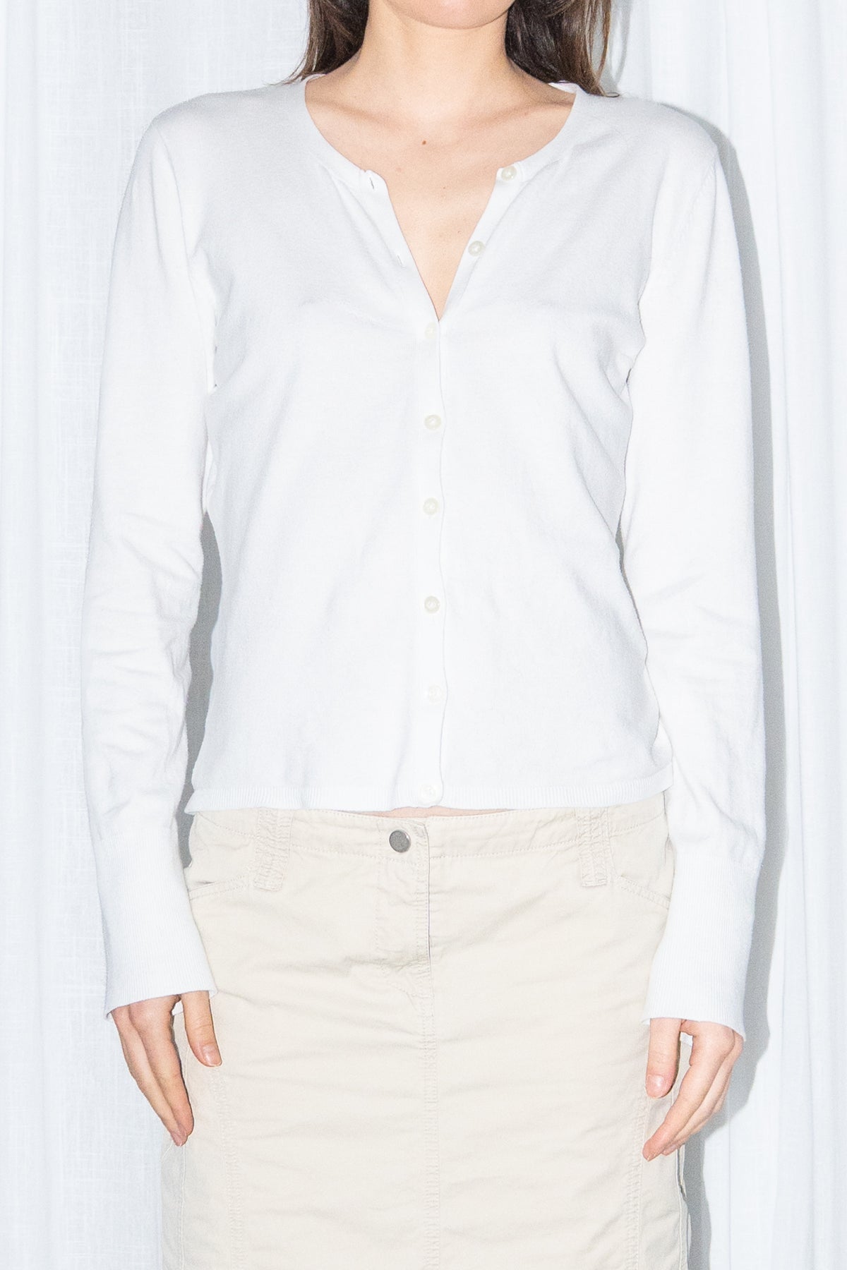 Close-up of a white cardigan with a beige midi skirt and black knee boots