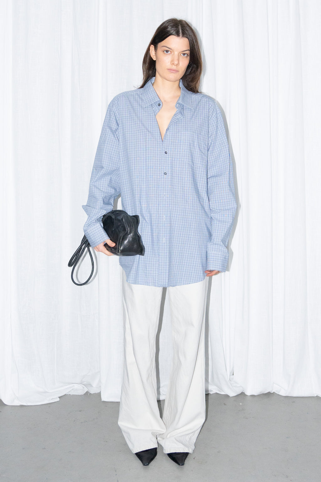 Model wearing a light blue oversized button-up shirt with white wide-leg trousers