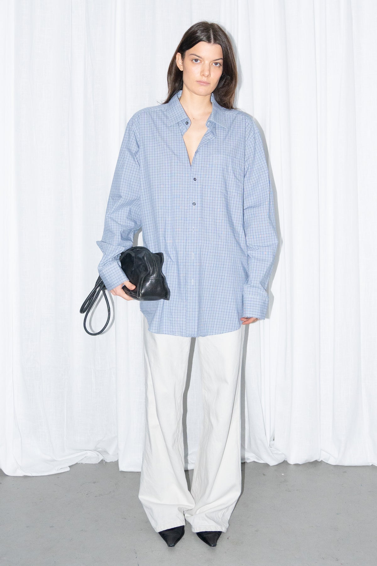 Model wearing a light blue oversized button-up shirt with white wide-leg trousers