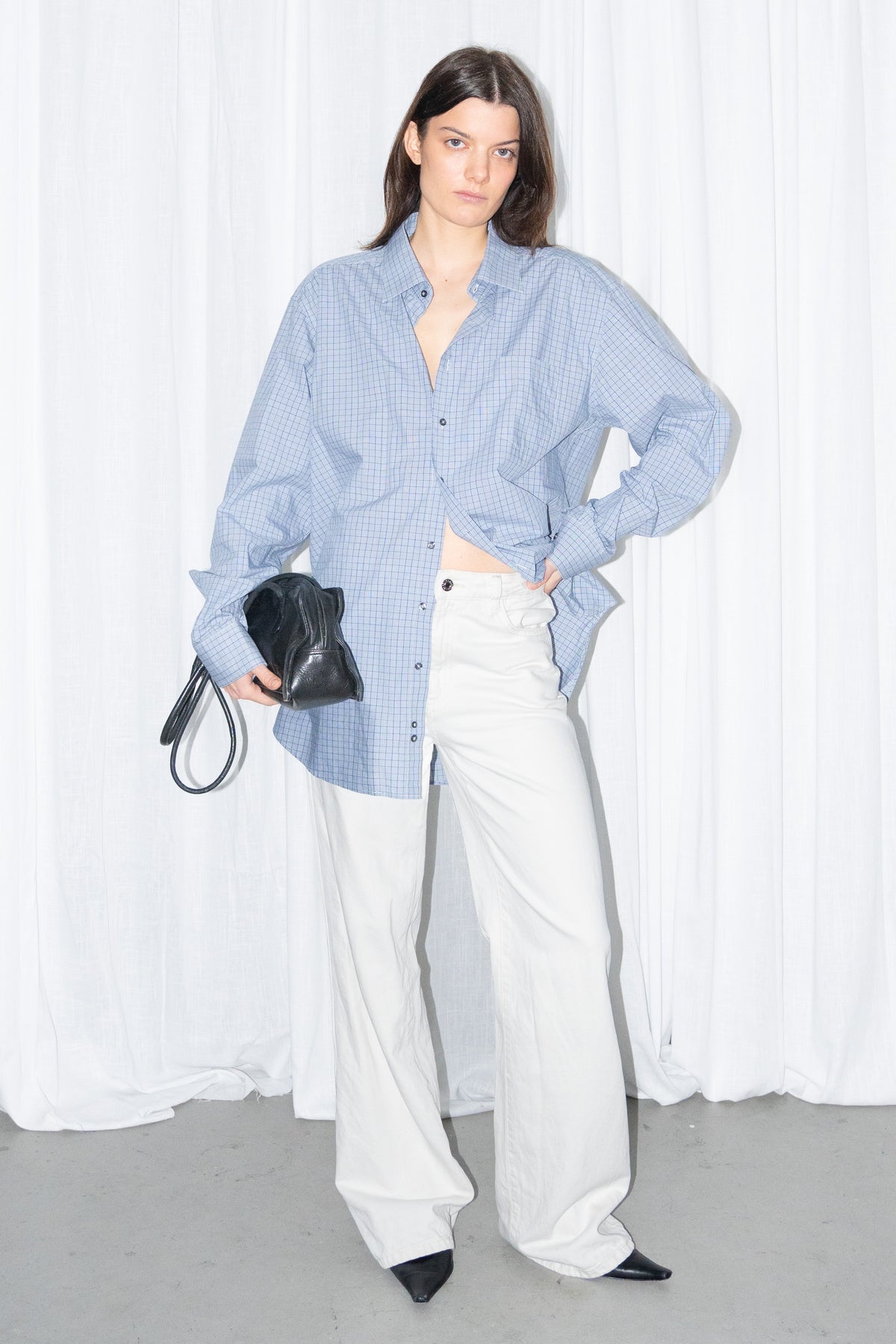 Model posing in a light blue oversized button-up shirt with white wide-leg trousers