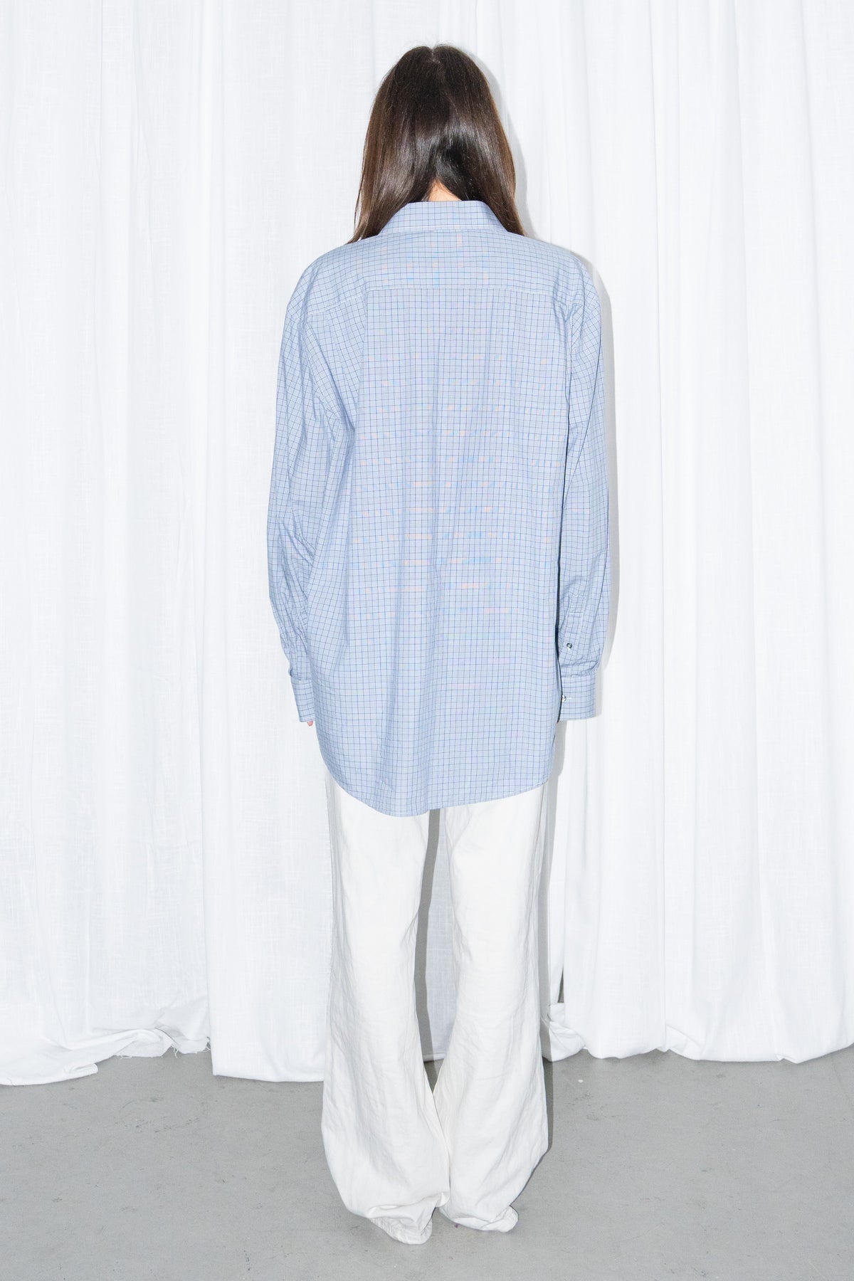 Back view of a light blue oversized button-up shirt with white wide-leg trousers