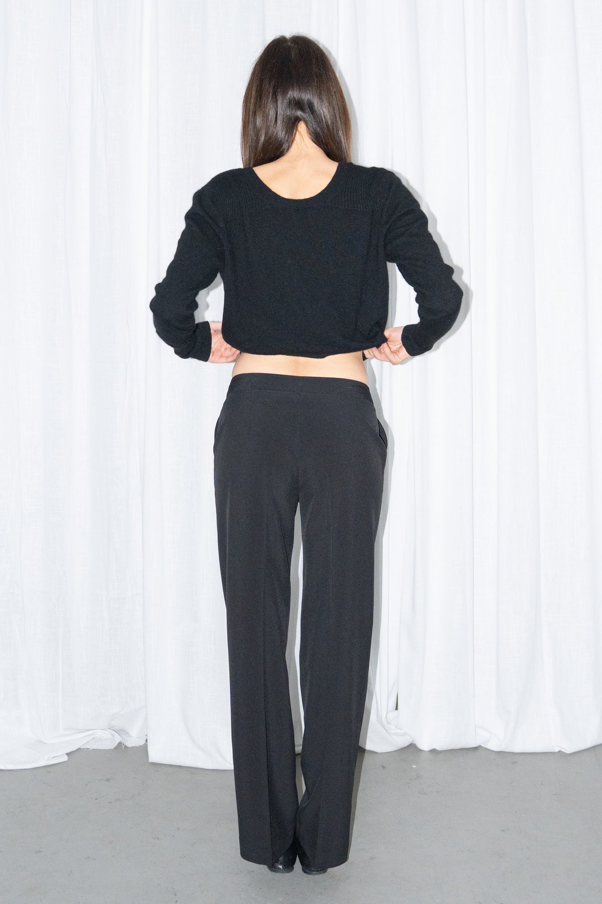 Front view of black tailored straight trousers with a black chunky knit cardigan
