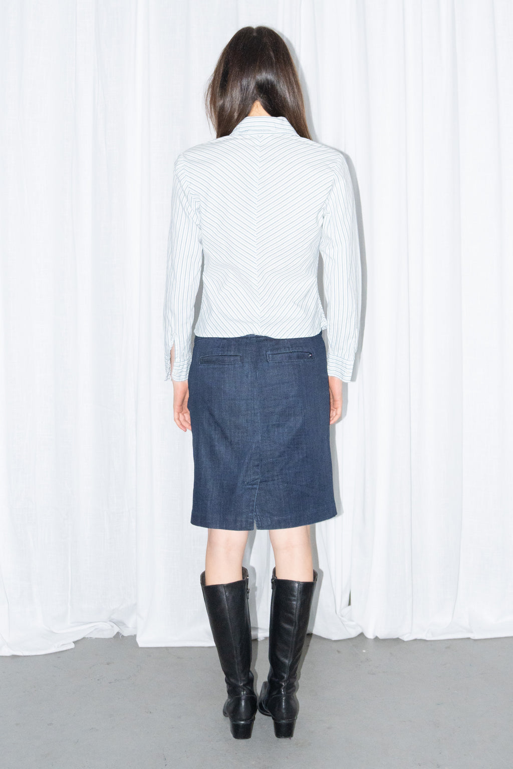 Model wearing a light blue striped fitted shirt with a dark blue denim knee-length skirt
