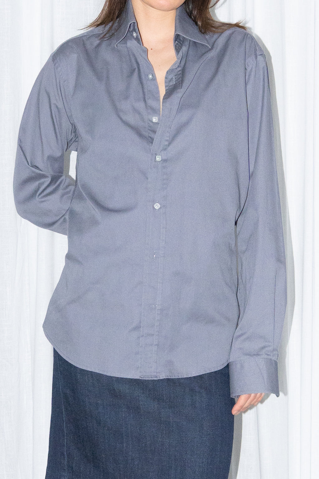 Close-up of a grey button-up shirt with a dark blue denim skirt and a burgundy leather bag