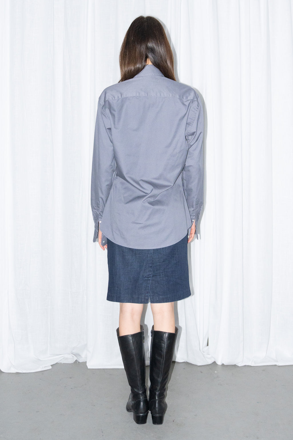 Back view of a grey button-up shirt with a dark blue denim skirt and a burgundy leather bag