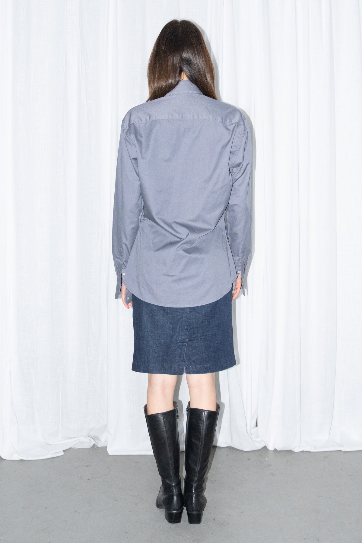 Back view of a grey button-up shirt with a dark blue denim skirt and a burgundy leather bag
